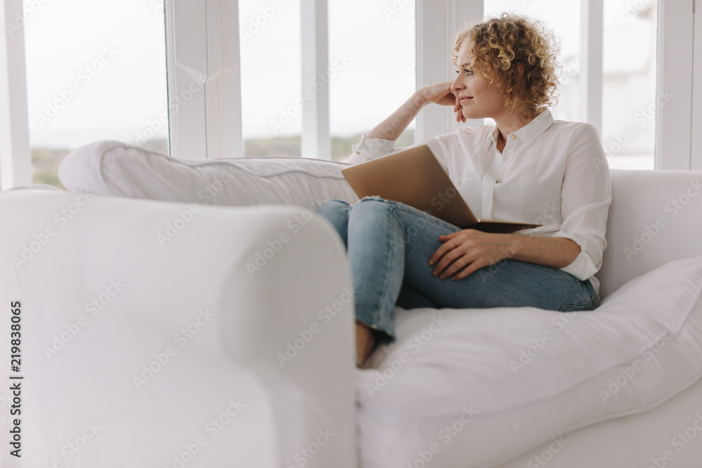 Woman sitting on couch at home with a laptop