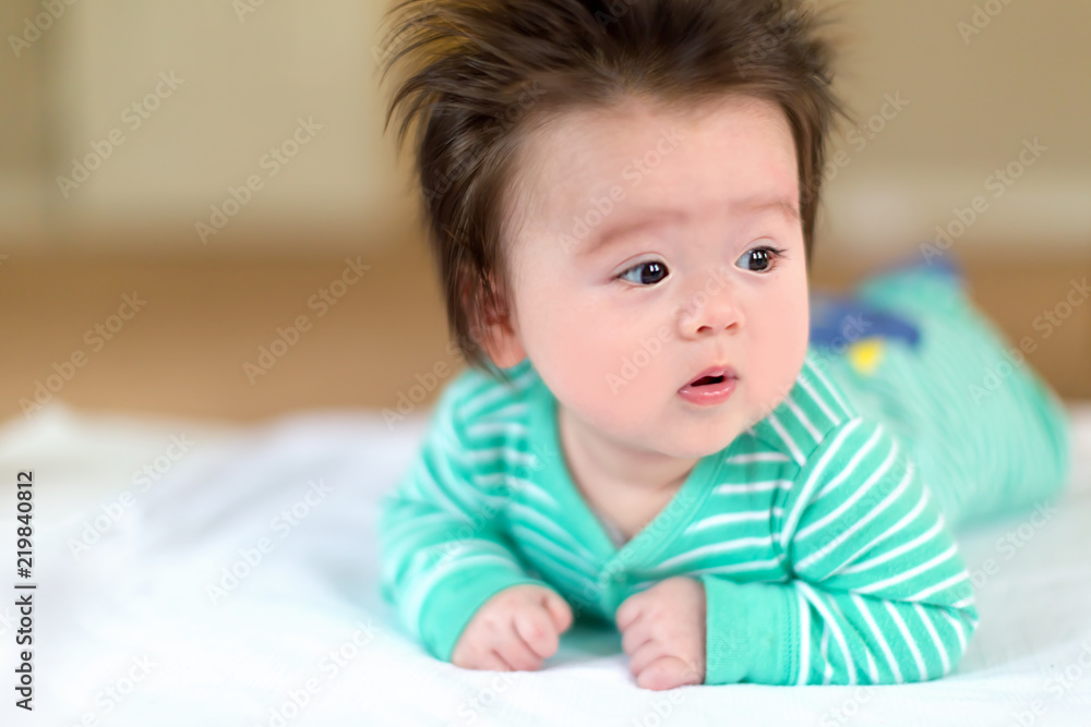 穿着睡衣躺在地毯上的新生男婴