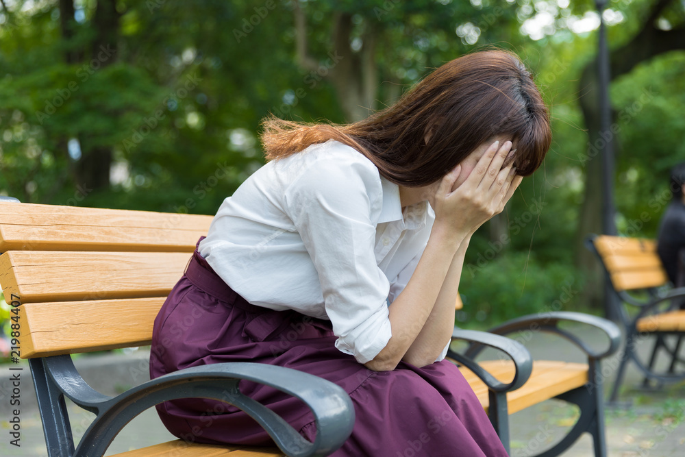 坐在公园长椅上的年轻亚洲女性