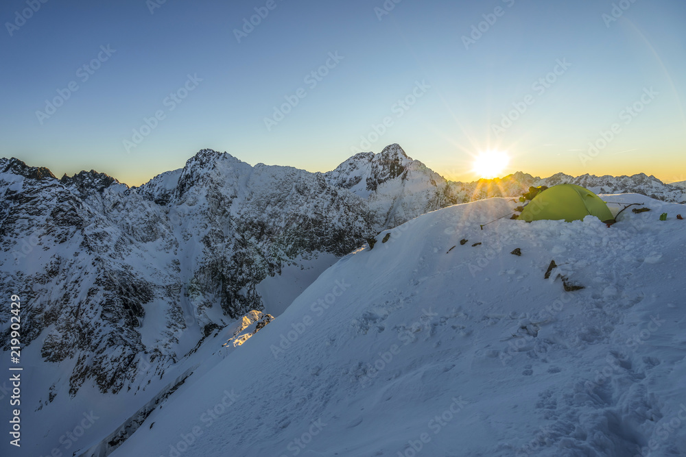 黄色帐篷搭在高山山顶上。冬天在白雪覆盖的山区露营。