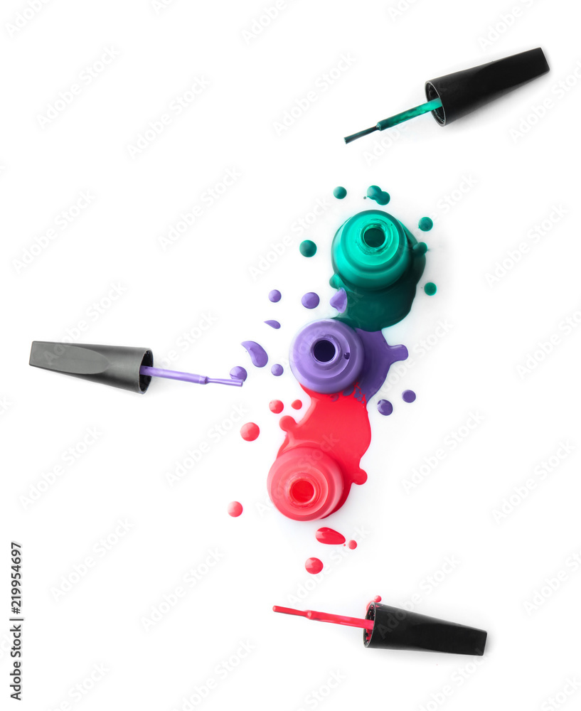 Open bottles of nail polishes with brushes on white background