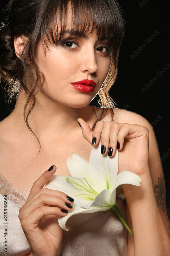 Beautiful young woman with professional manicure and flower on black background