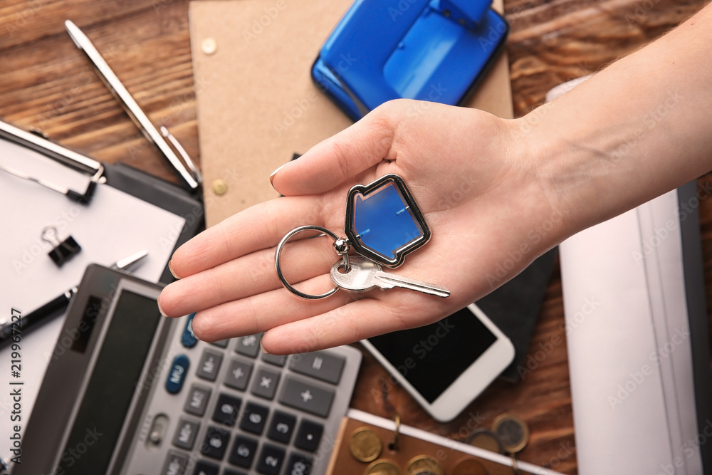 Woman holding key with trinket. Mortgage concept