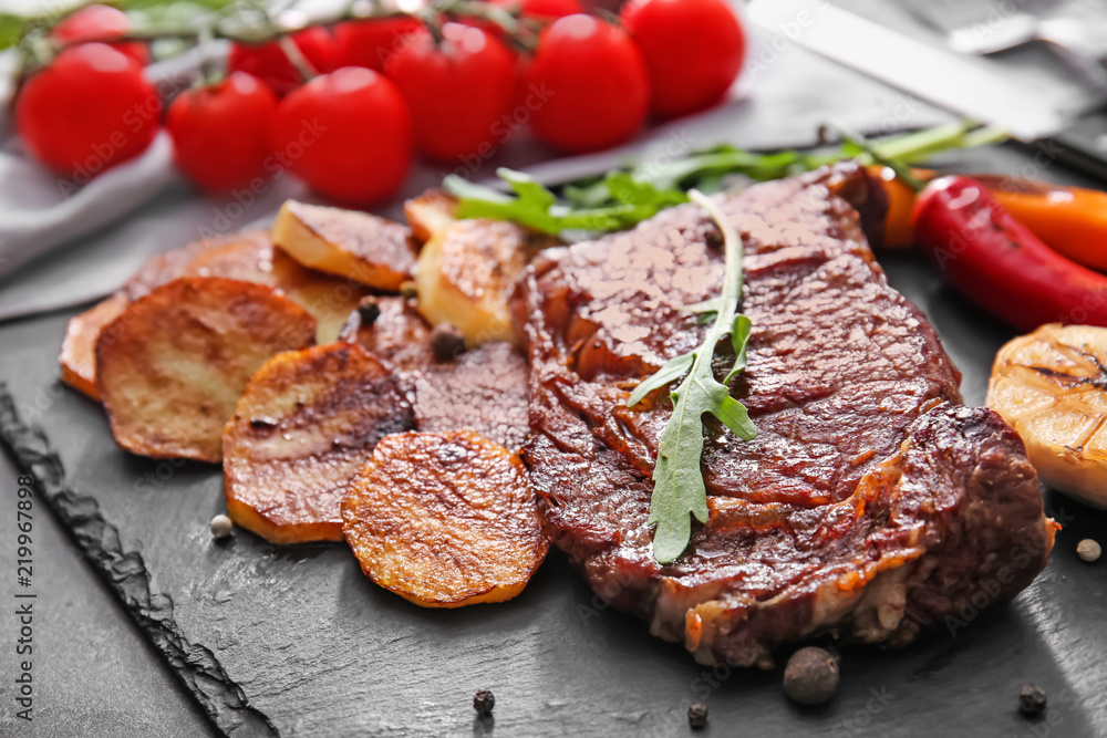 桌上放着美味烤肉、蔬菜和香草的石板，特写