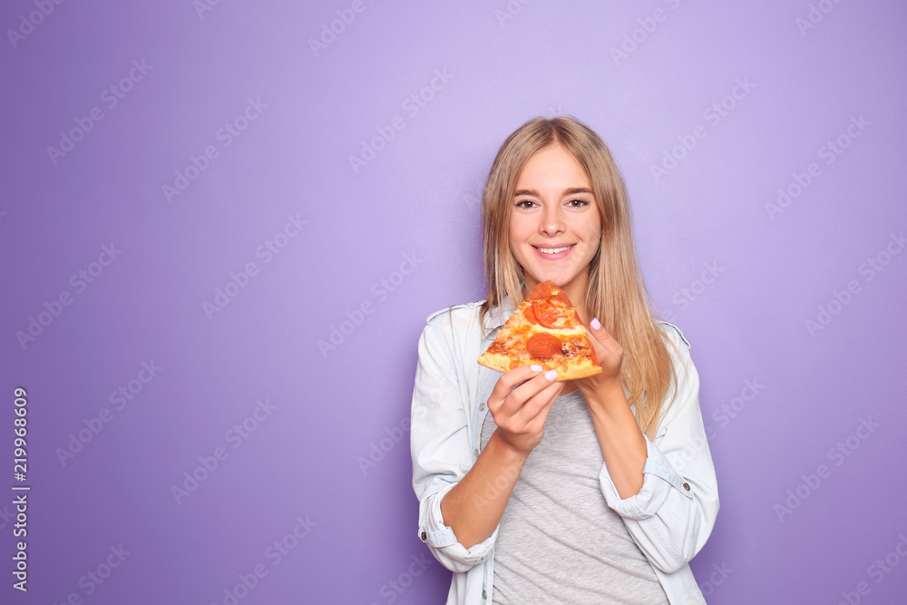 年轻女子在吃彩色背景的美味披萨