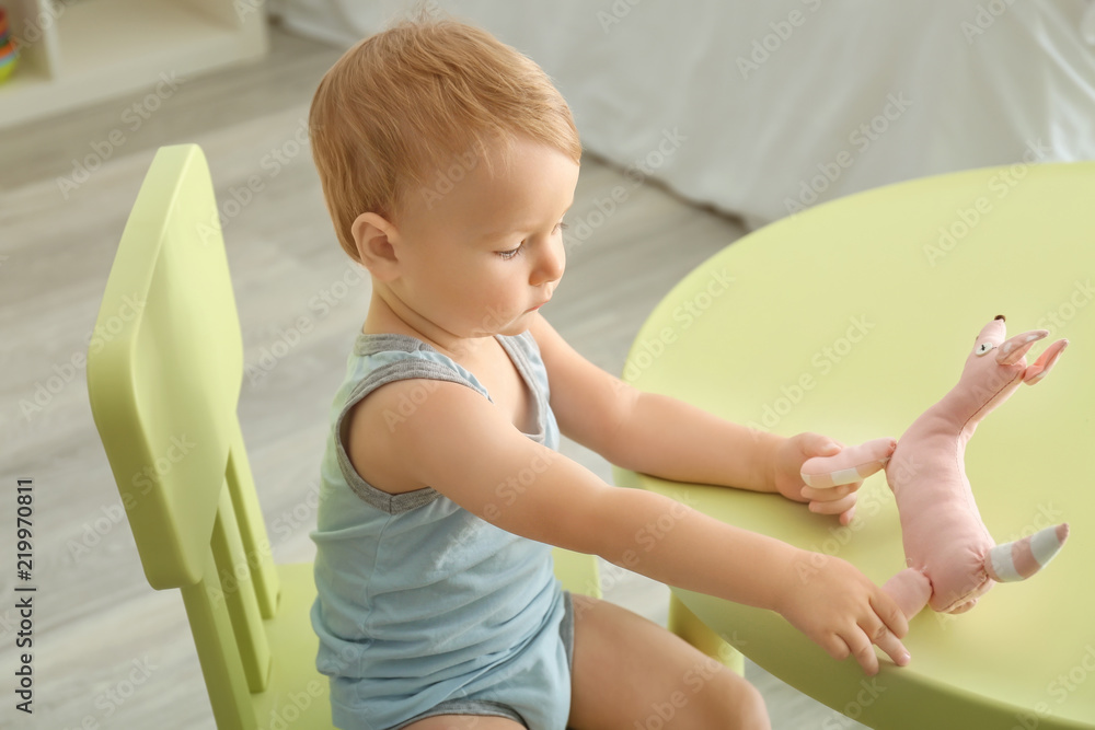 Cute little boy playing with toy at table indoors