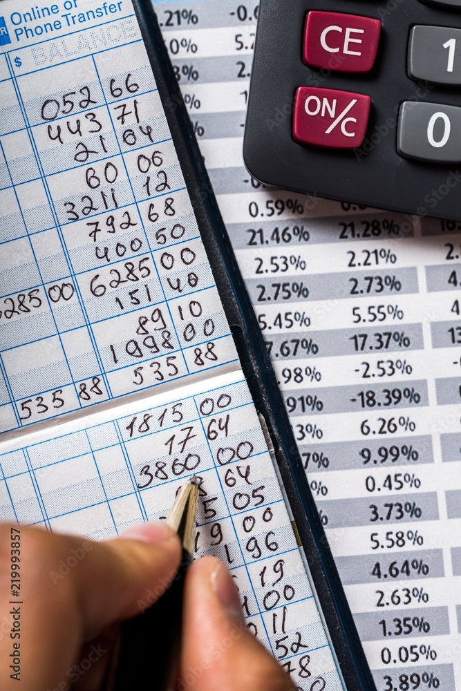 Close-up of a Businessman Writing on Bank Book with Calculator