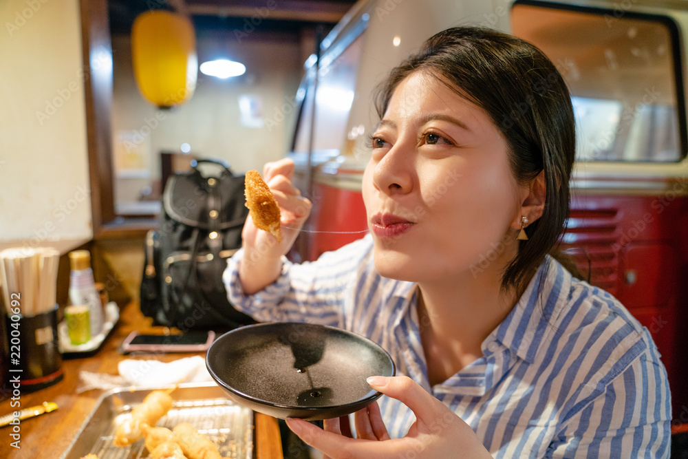 亚洲女人在居酒屋吃日本串。