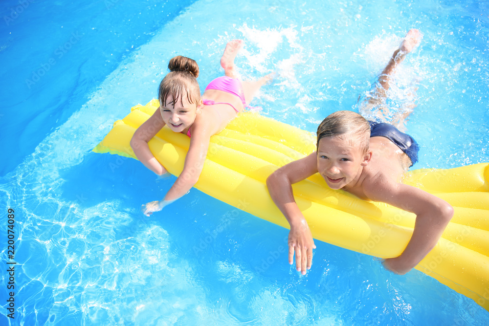 Cute children swimming in pool on summer day