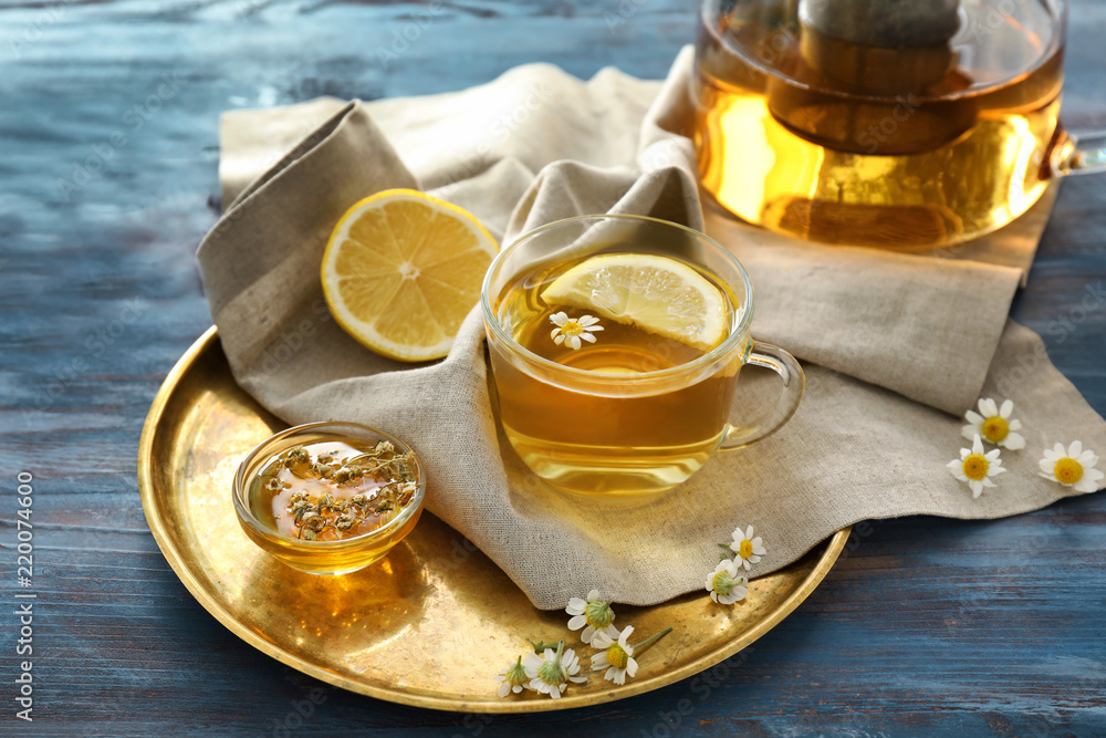 Cup of delicious camomile tea and honey on wooden table