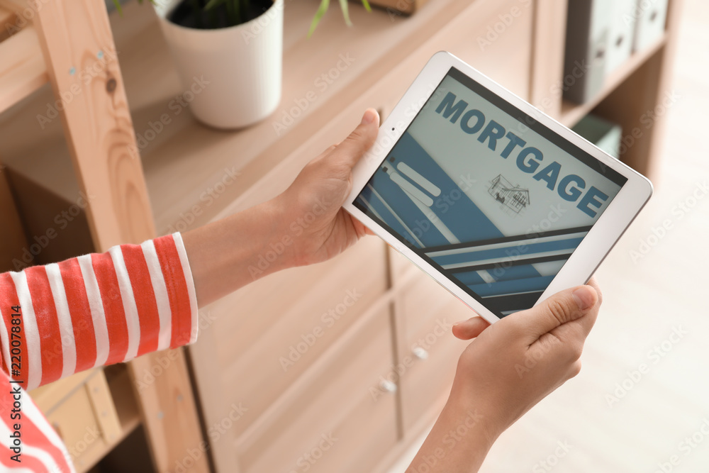 Woman using tablet computer to pay mortgage loan online at home