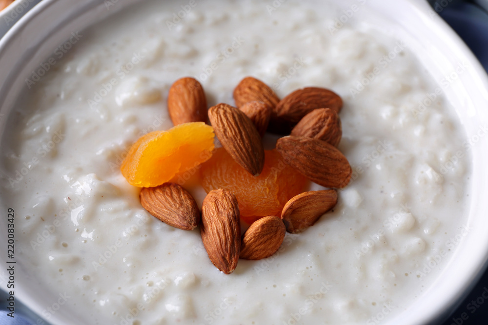 Delicious rice pudding with dried apricots and almonds in casserole, closeup