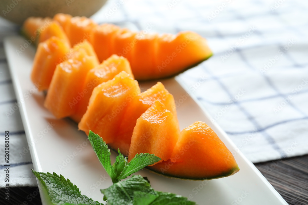 Plate with ripe cut melon on table, closeup