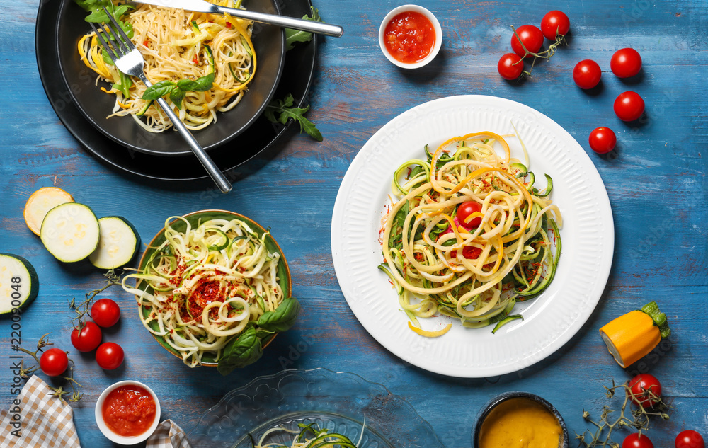 Tasty spaghetti with zucchini and sauces on color wooden table