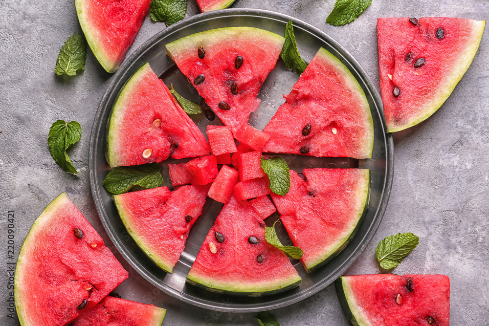 Metal tray with slices of ripe watermelon on grey table