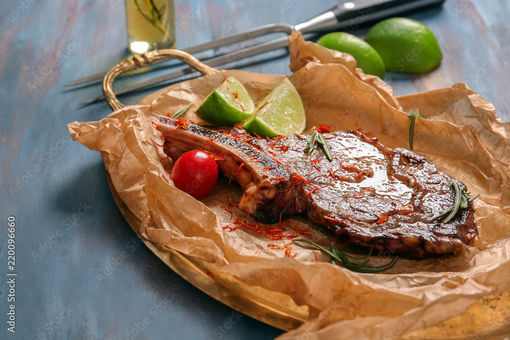 Metal tray with delicious grilled steak on wooden table