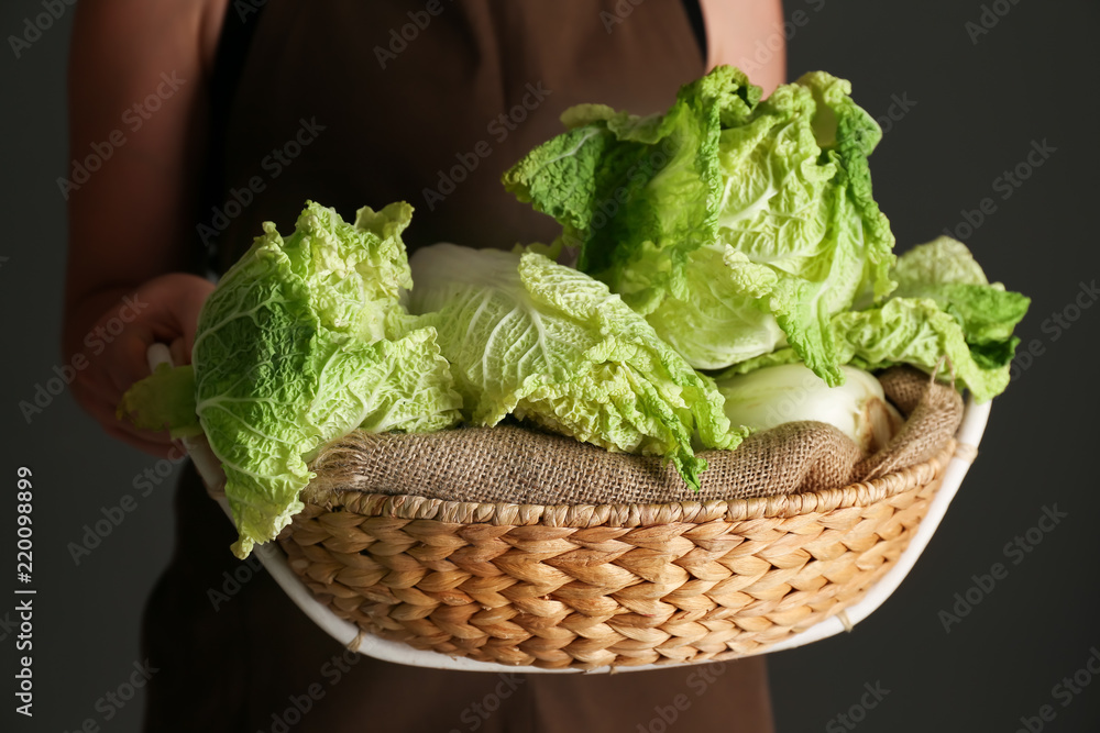 女人拿着柳条篮子，里面放着新鲜成熟的卷心菜，特写