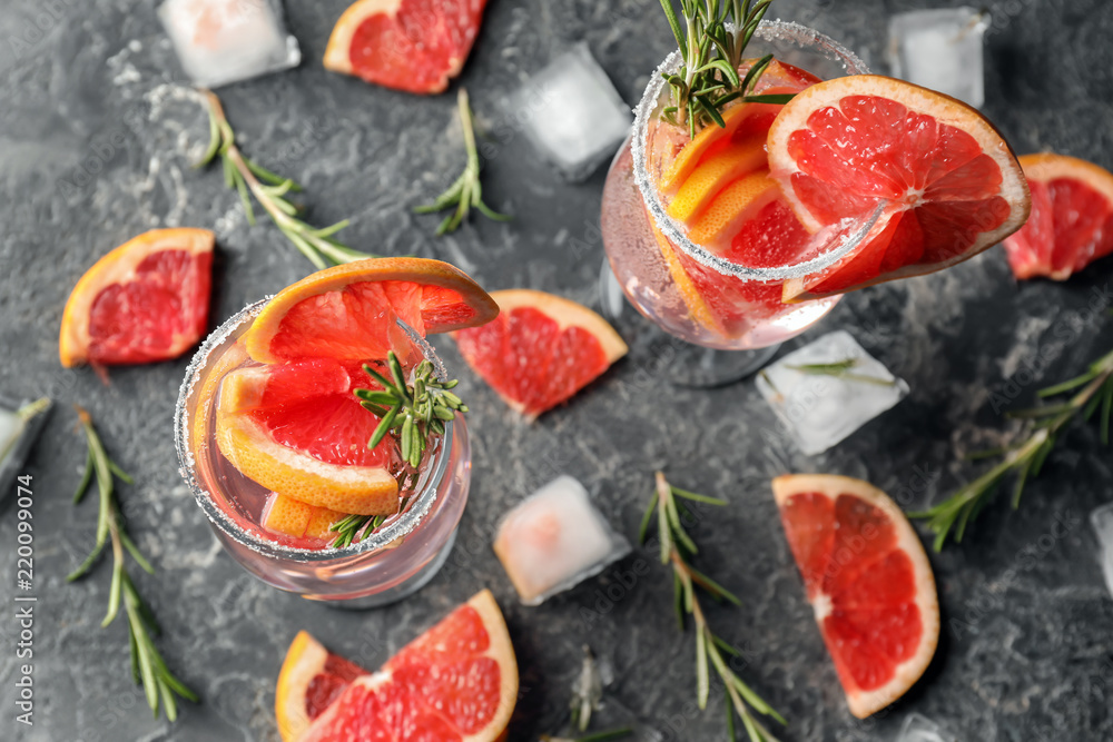 Fresh grapefruit cocktail with rosemary in glasses on grey table