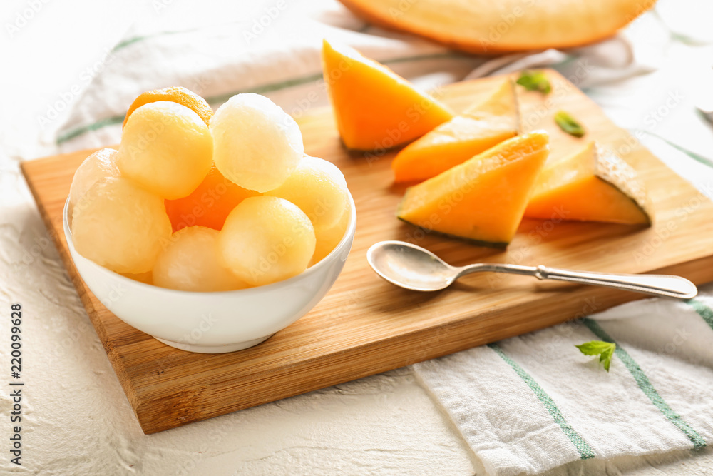 Board with sliced melon and delicious balls on white table