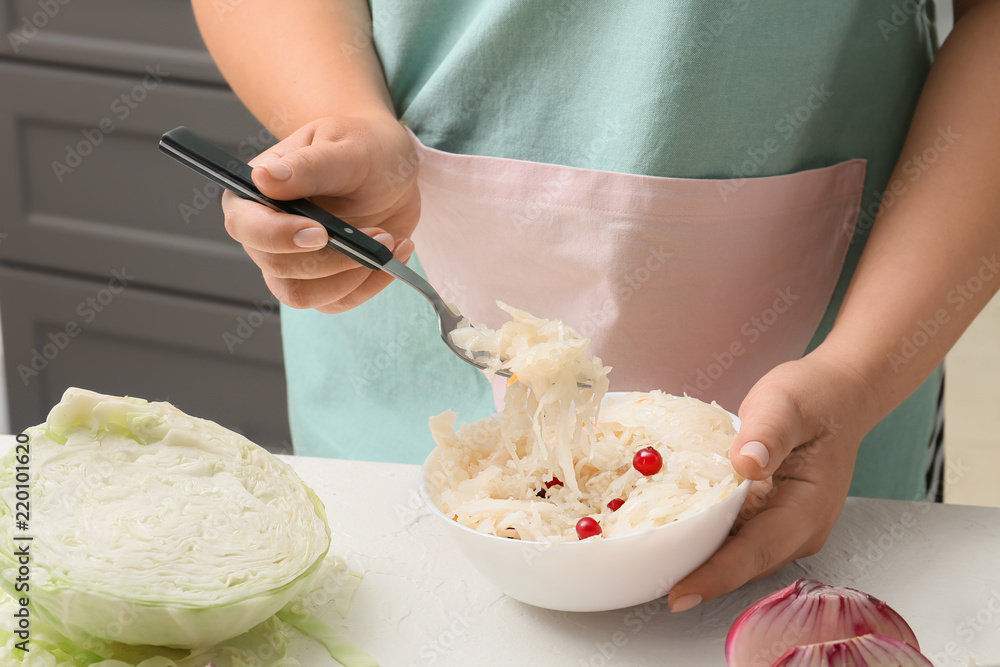 餐桌上用叉子从碗里拿自制酸菜的女人