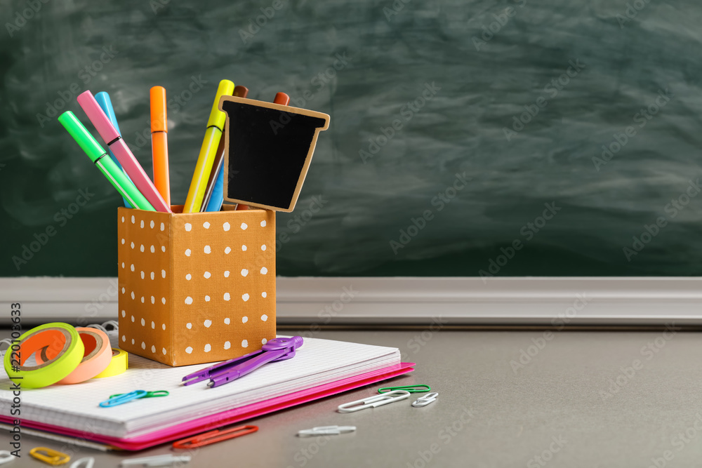 School stationery on table against dirty chalkboard