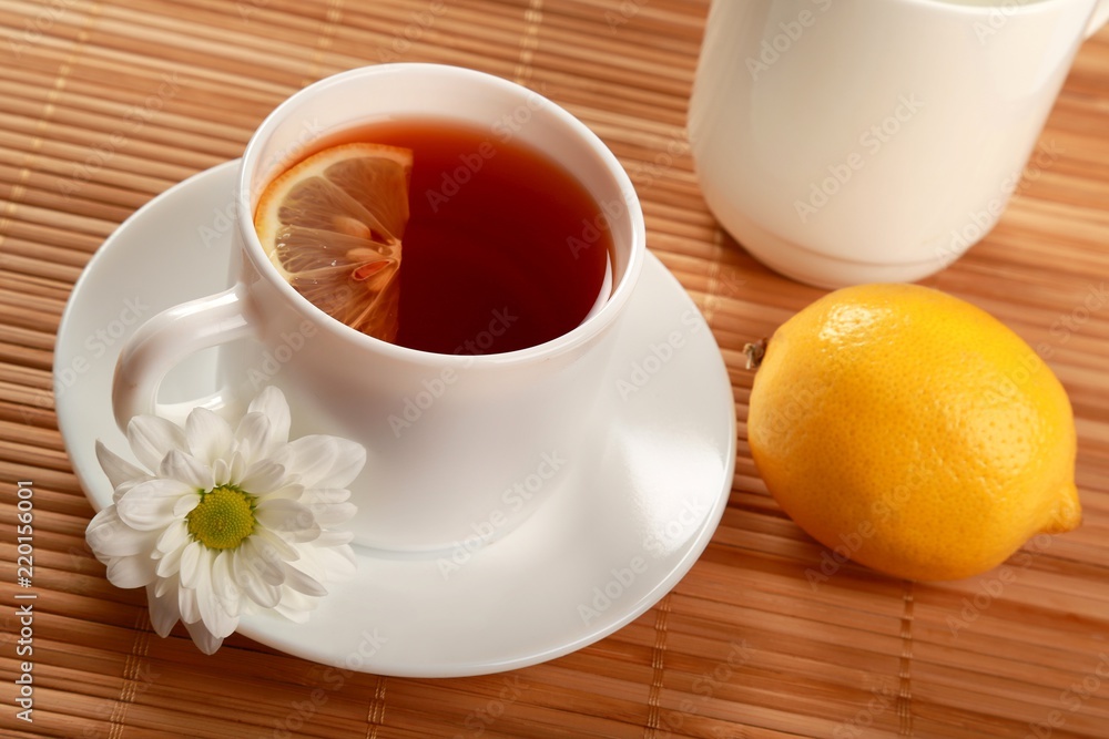 Tea with lemon slice, whole lemon and flower