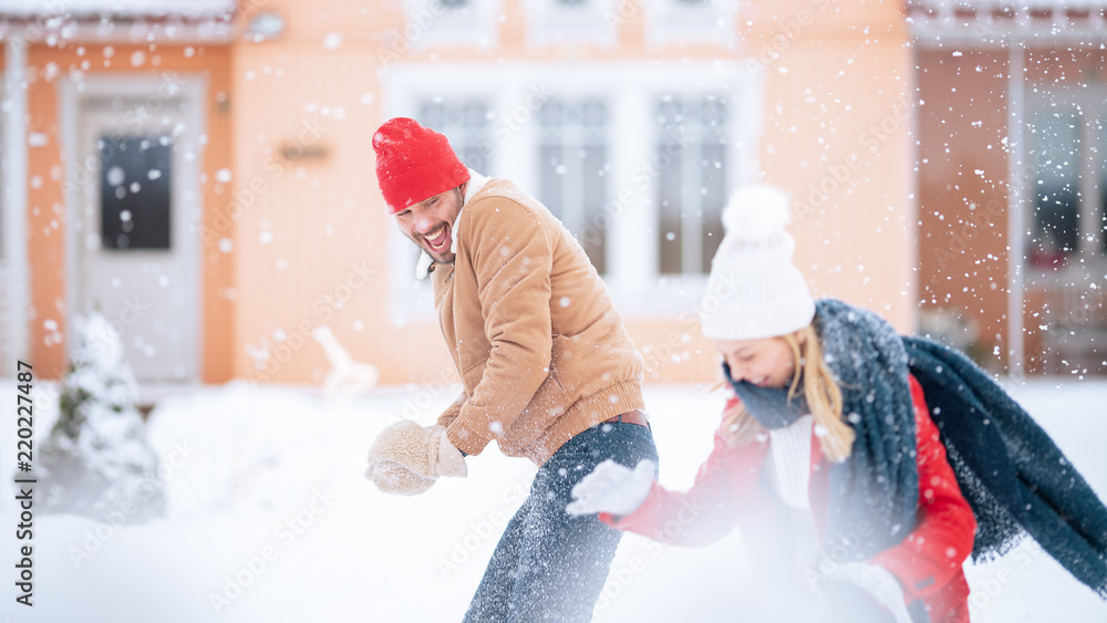 年轻漂亮的情侣在下雪时互相扔雪球。快乐的男女玩耍