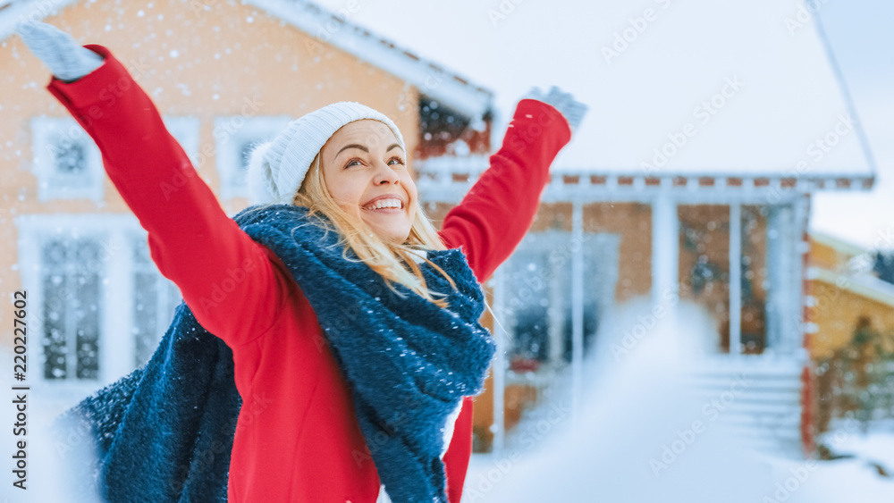 Beautiful Young Smiling Woman Jumps and Spins Under Falling Snow. Girl in a Red Coat with a Scarf En