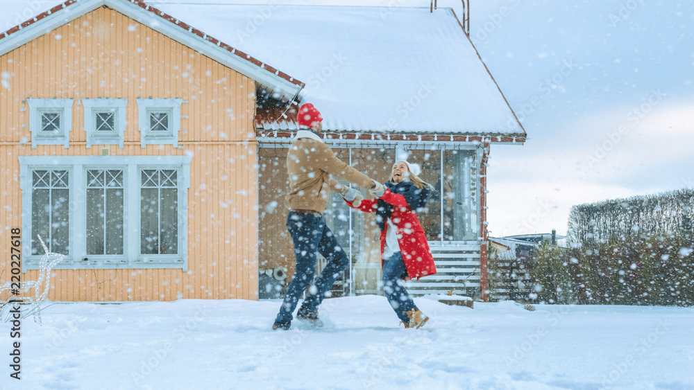 年轻漂亮的情侣在飘落的雪地里跳舞和旋转。快乐的男人和女人在冬天玩得很开心