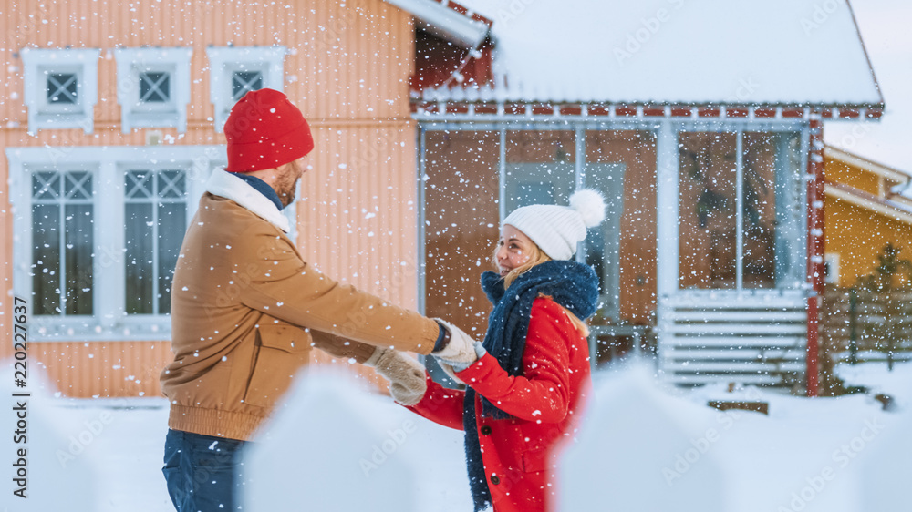 年轻漂亮的情侣在新雪覆盖的院子里旋转跳舞，冬日落S