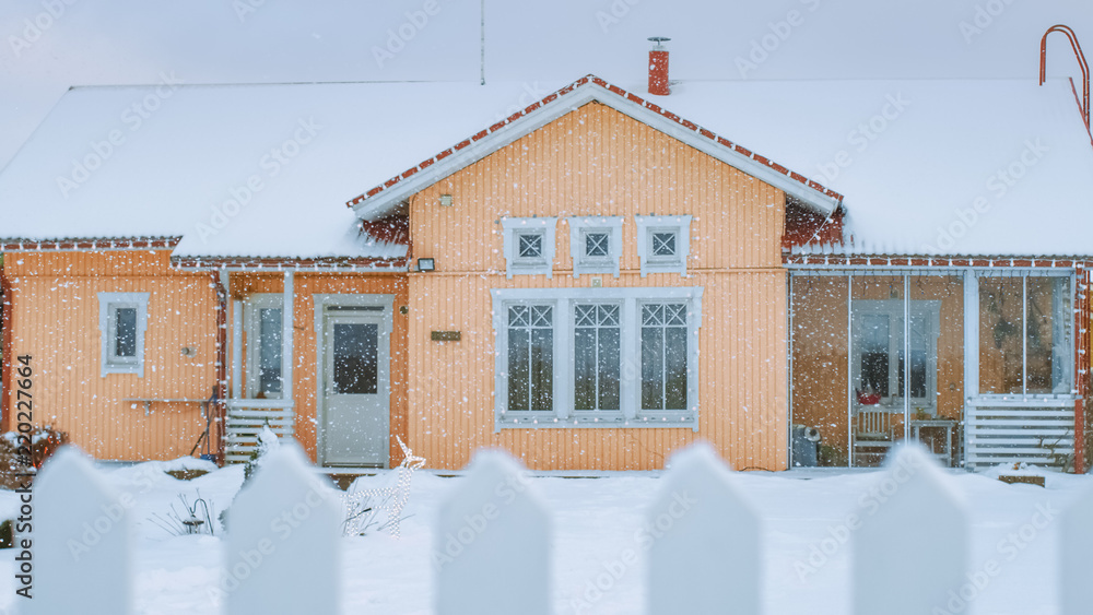 Idylic House的美丽冬季景色，有华丽的后院和围栏。柔软的雪落在墙上