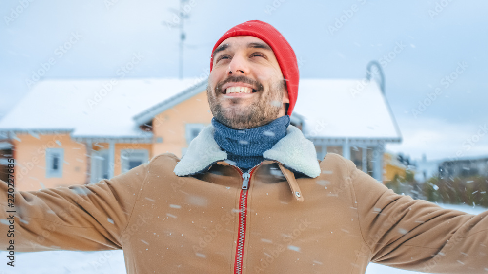 一个美丽的冬日，一个英俊微笑的男人在后院散步的肖像。柔软的雪