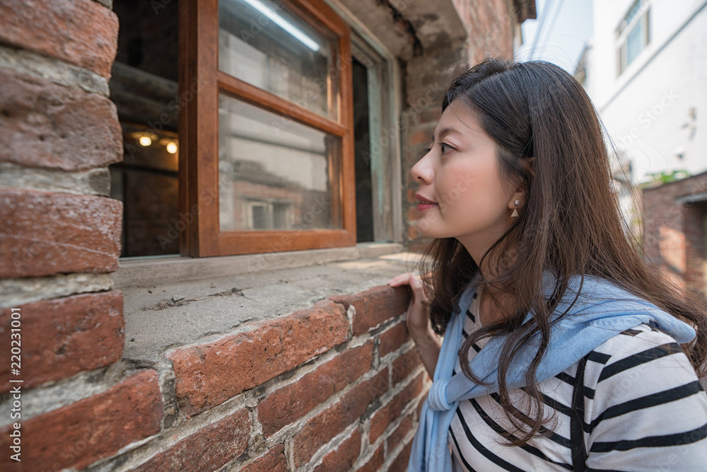 亚洲女人透过窗户往里看。