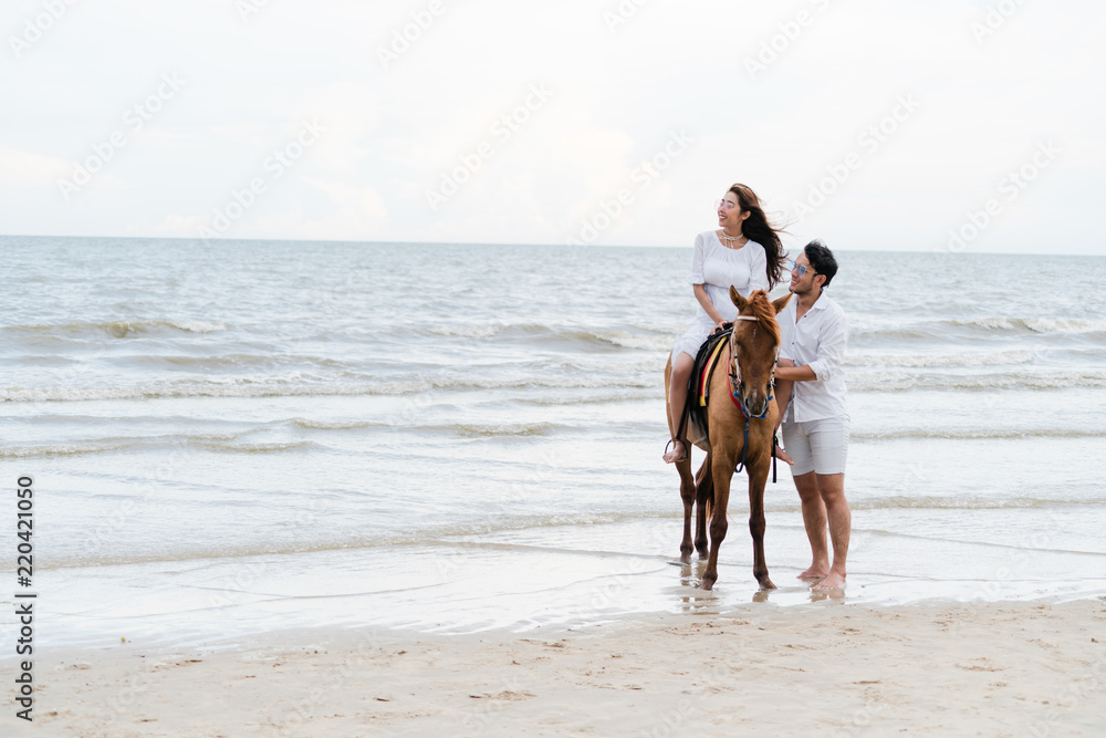 年轻夫妇在热带海滩上骑马。