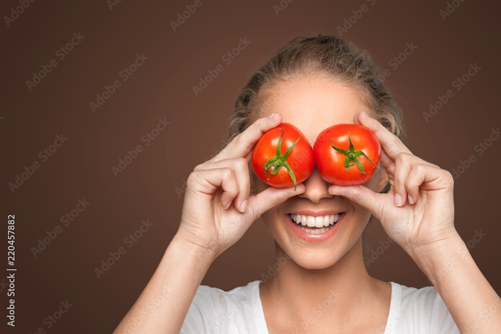 Beautiful laughing woman holding two ripe tomatoes before her