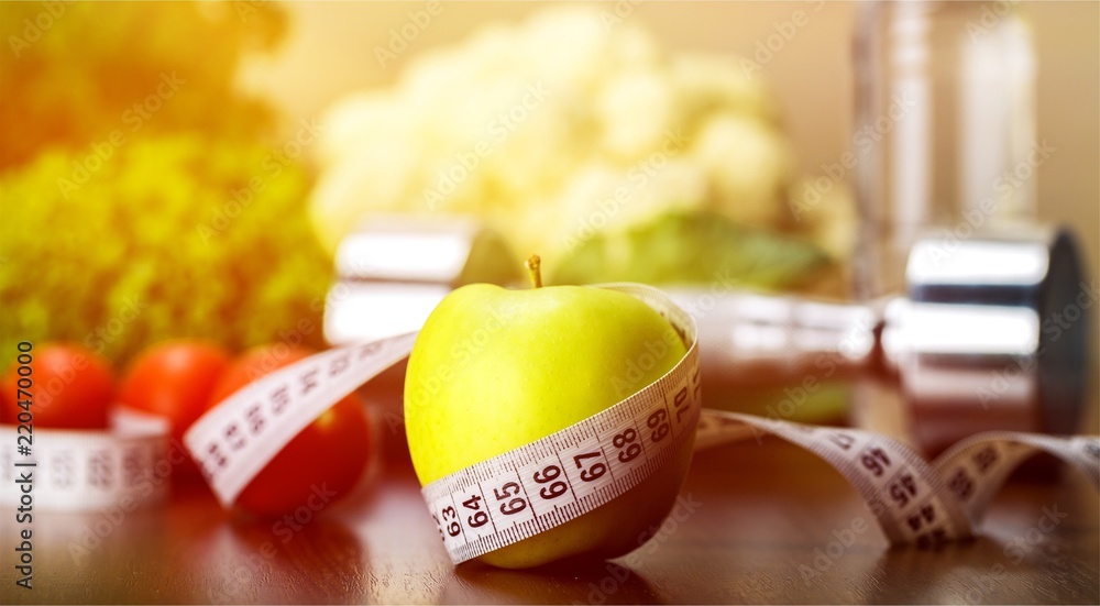 Dumbbell with bottled water , measuring tape and food isolated