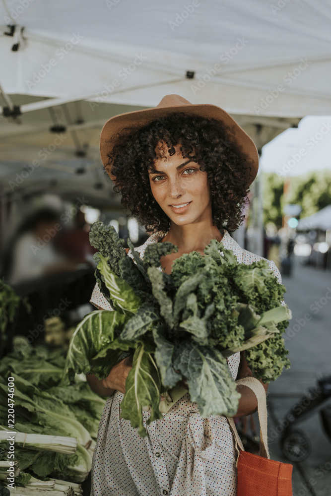 Beautiful woman buying kale at a farmers market