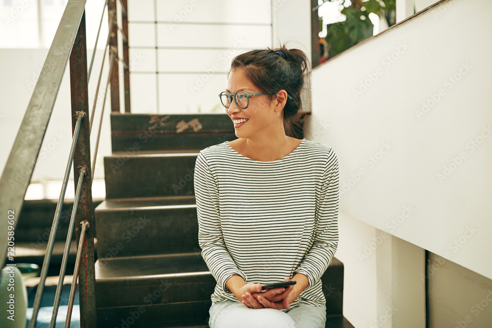 坐在办公室楼梯上大笑的年轻亚洲女商人阅读