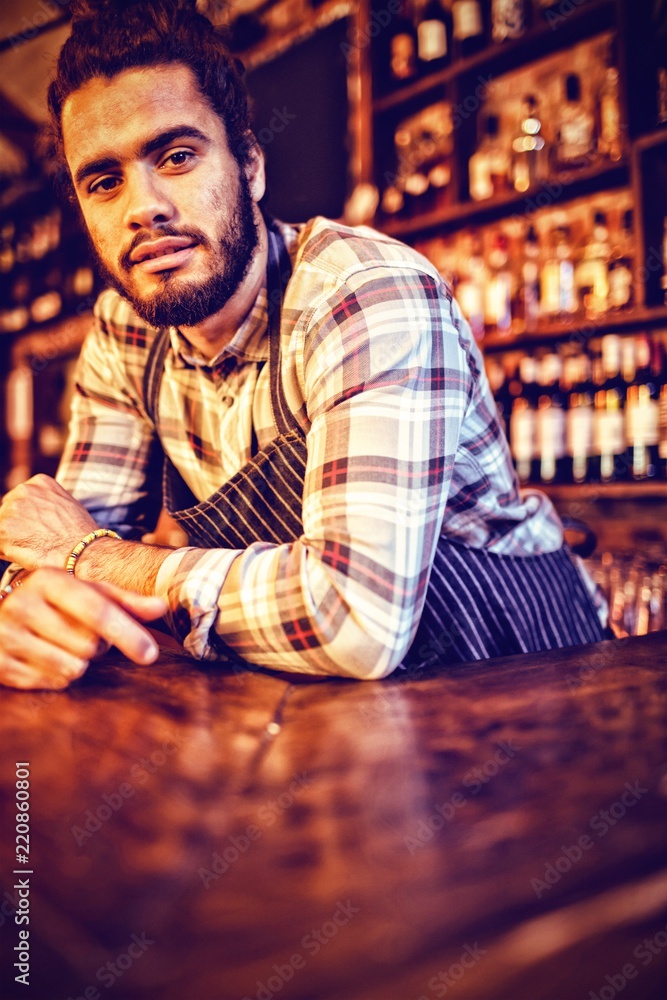 Portrait of waiter leaning at counter 