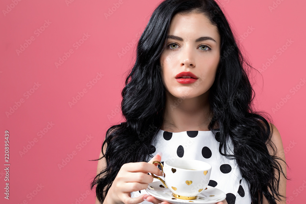 Young woman drinking coffee on a solid background