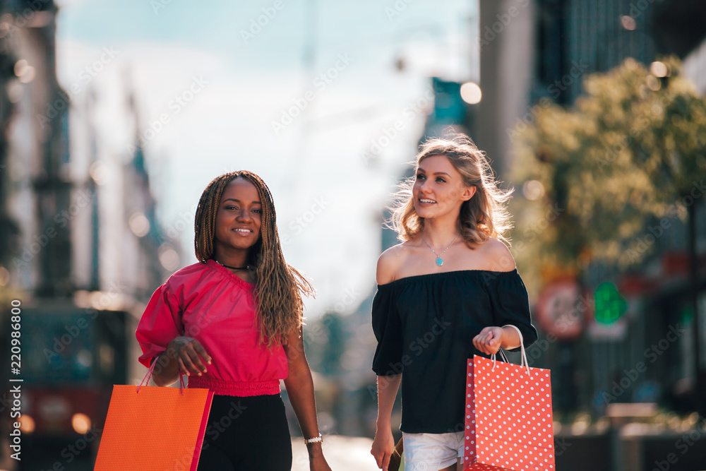 Happy female friends with shopping bags, multi ethnic group of people hanging out in the city