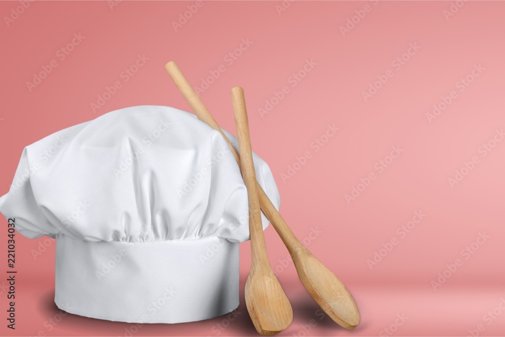 White cooks cap and wooden spoons on wooden table