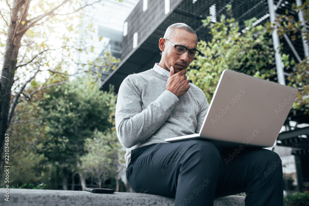 Businessman working on laptop computer sitting outdoors