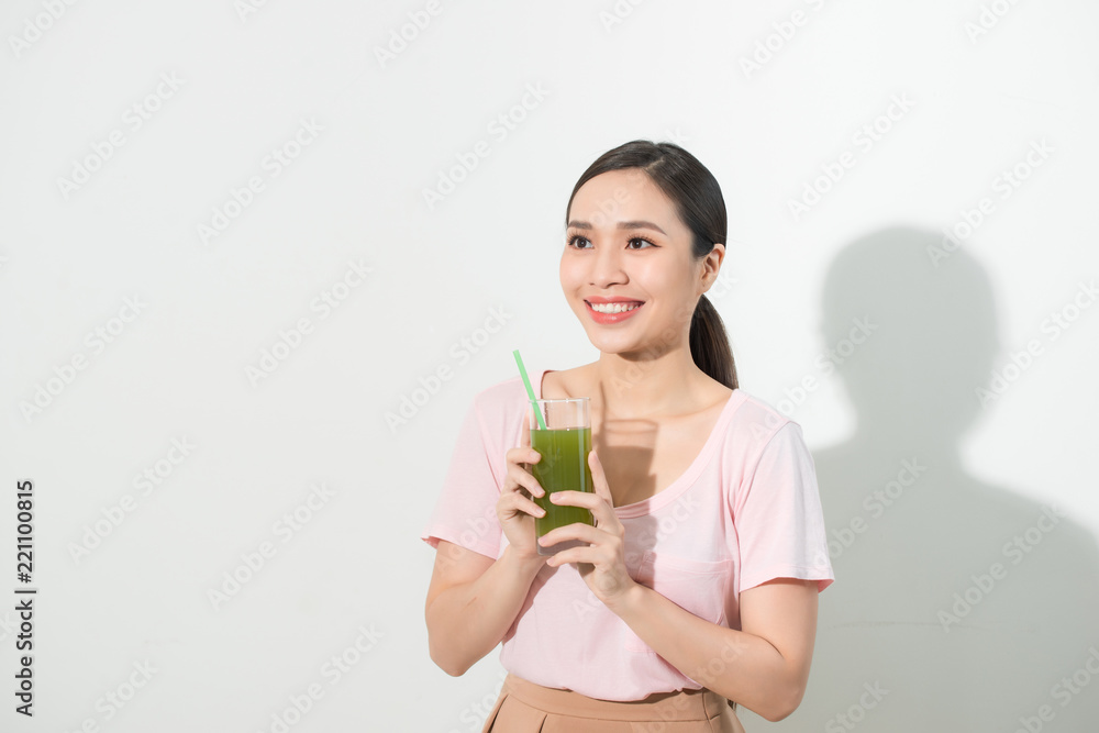 Go green. Young beautiful woman enjoying a healthy raw fruit vegetable juice. Studio shot.