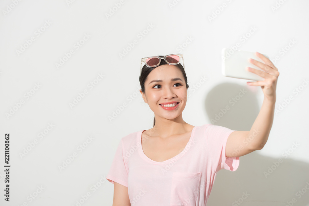 Portrait of a young attractive woman making selfie photo on smartphone isolated on a white backgroun