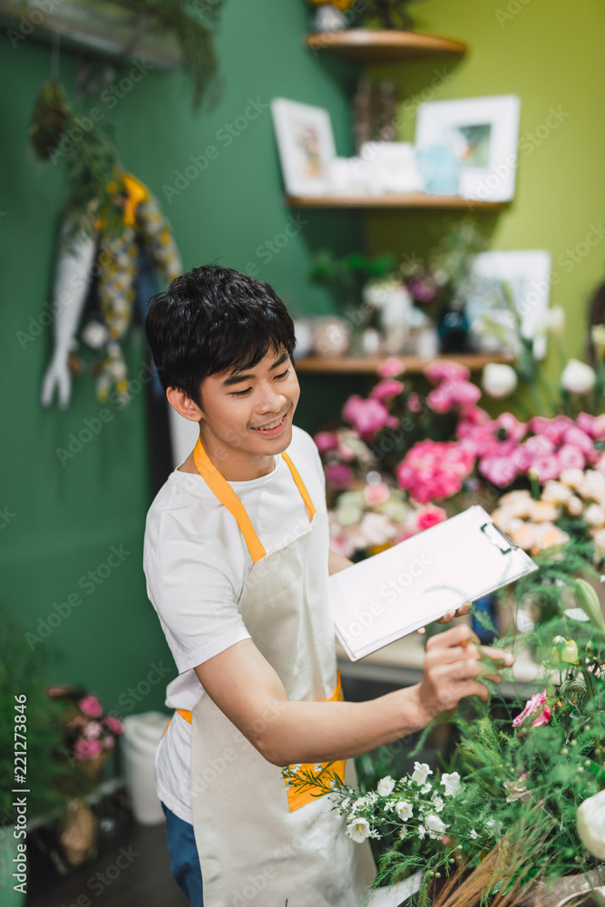 一位年轻快乐的亚洲男花店老板在店里工作