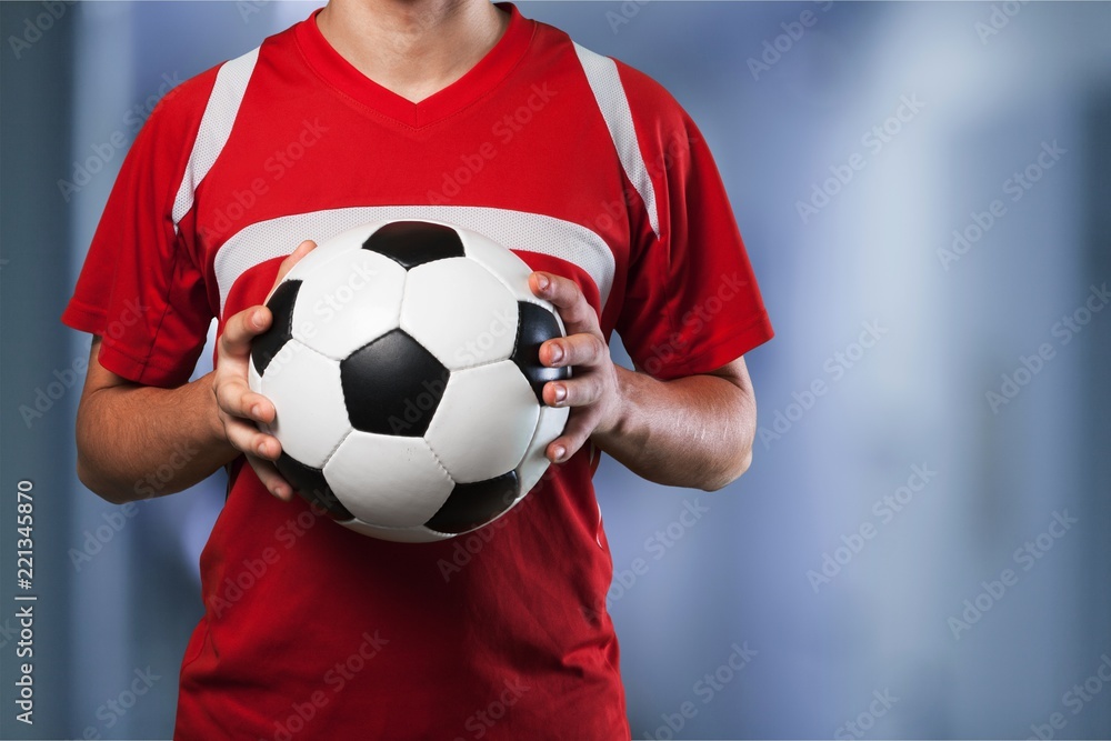 Soccer player is holding ball on  background