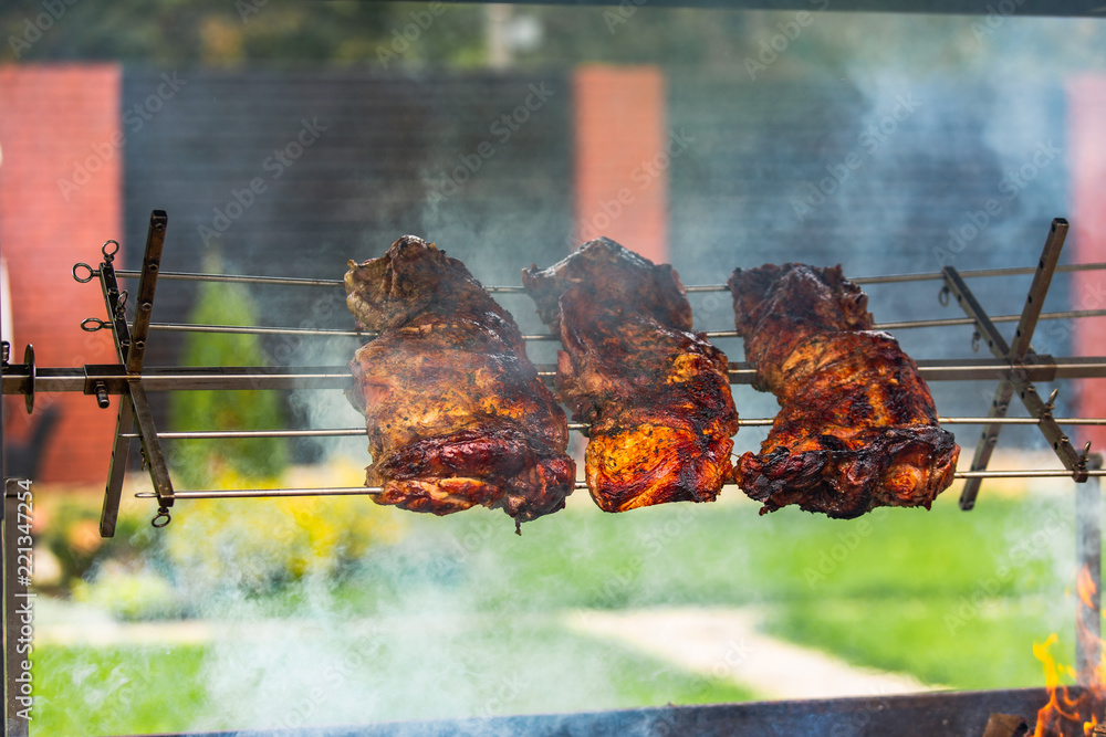 Shish kebab roasts on the grill. Three pieces of pork are under the fire in the smoke in the street 