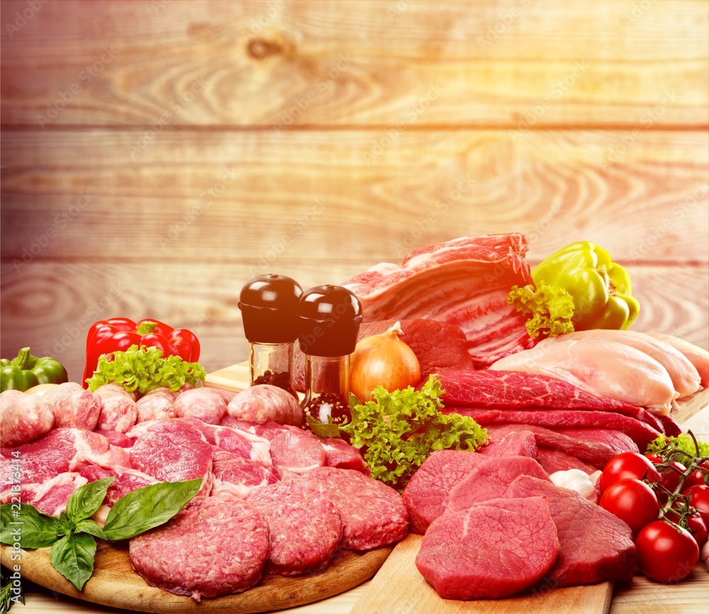 Fresh raw meat with vegetables on brown wooden table at wooden