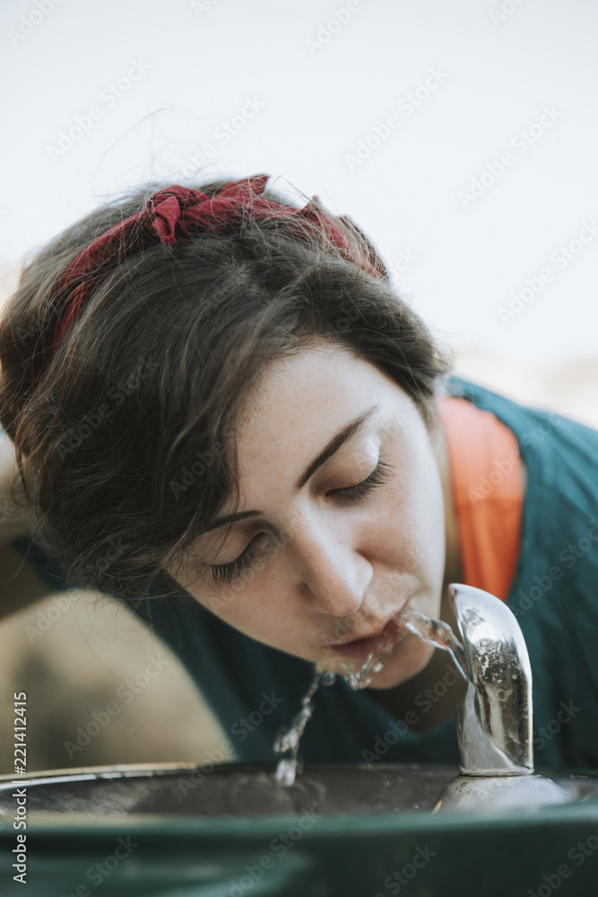 Woman drinking water from a water fountain